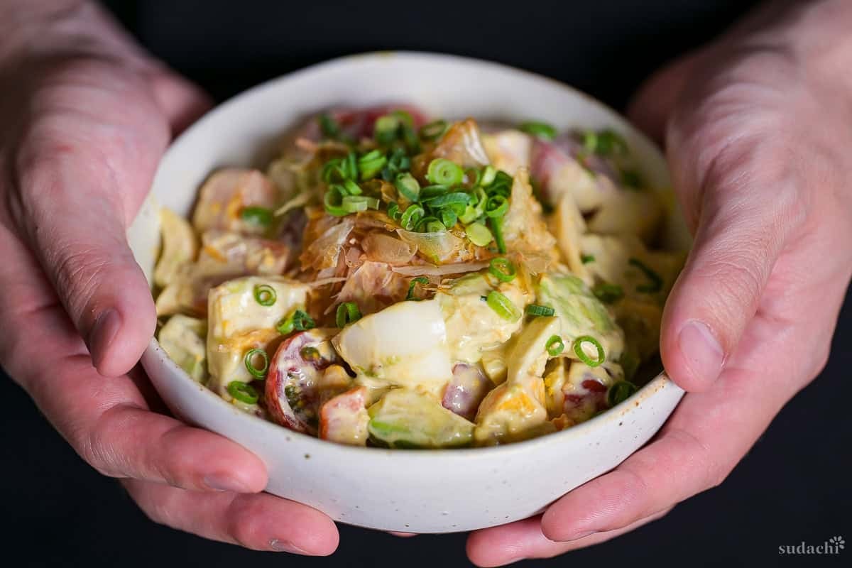 Yuto Omura holding up Japanese style avocado egg salad in an off-white bowl