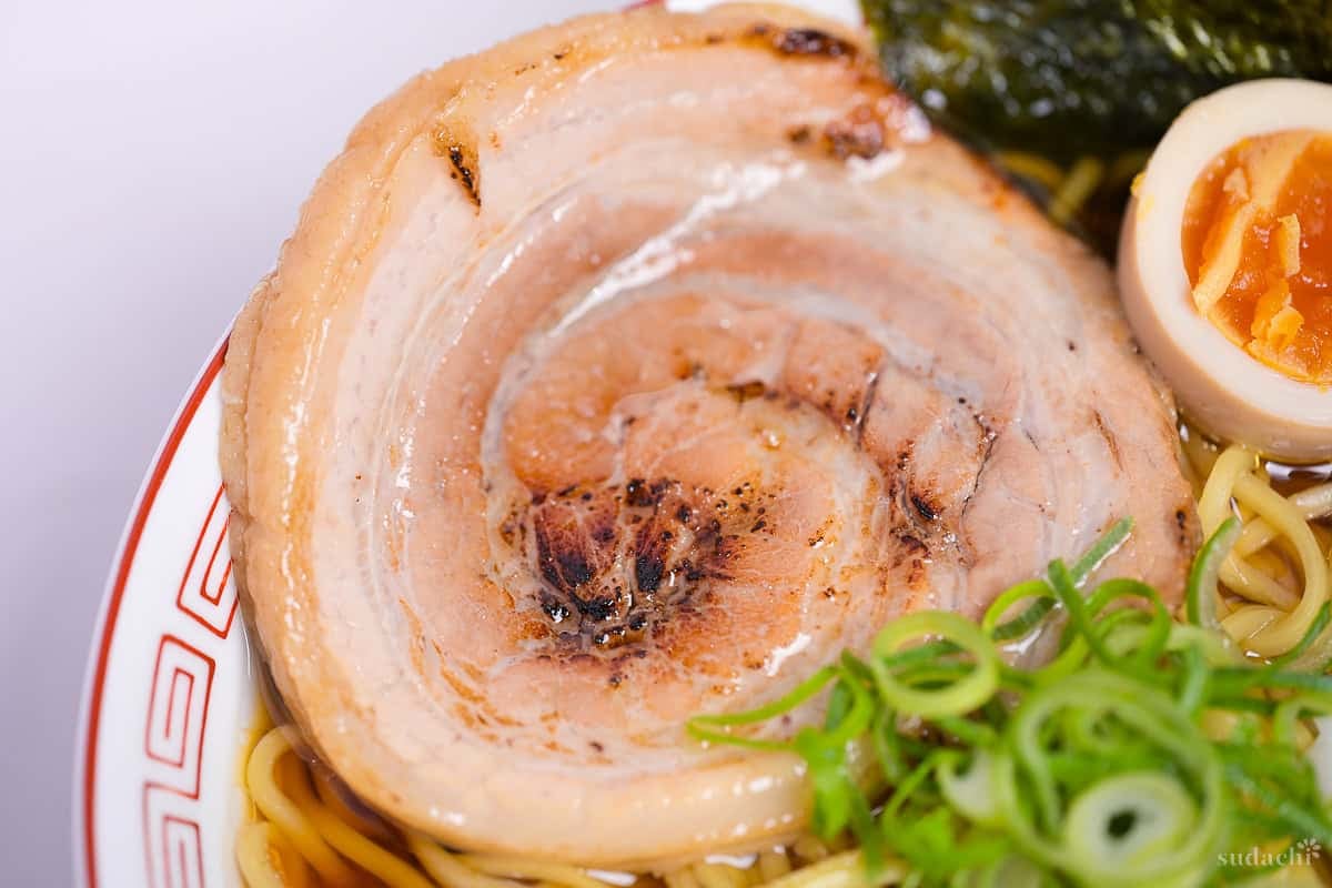 close up of lightly charred pork chashu in a bowl of ramen