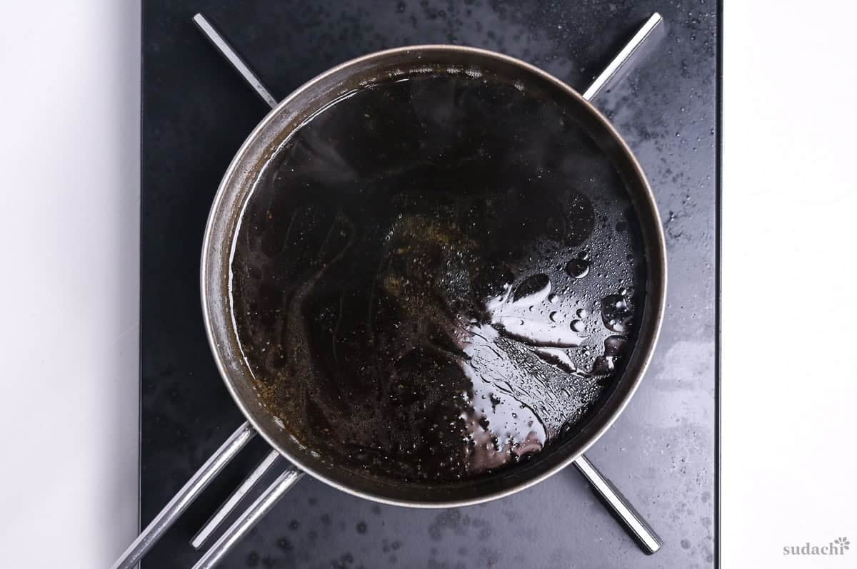 simmering leftover pork chashu marinade in a saucepan on the stove