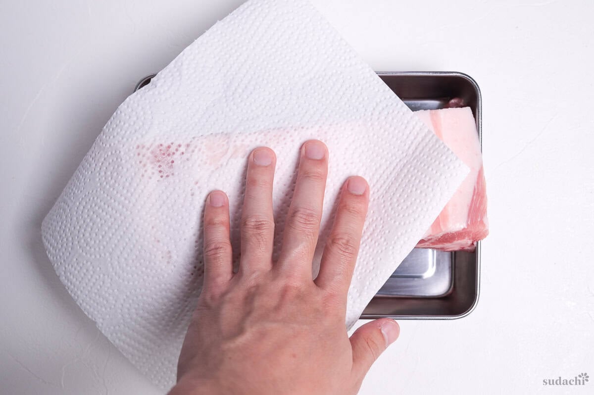 patting pork belly dry with kitchen paper