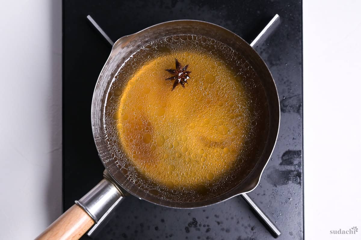 pork stock, condiments and star anise simmering in a small pot on the stove top