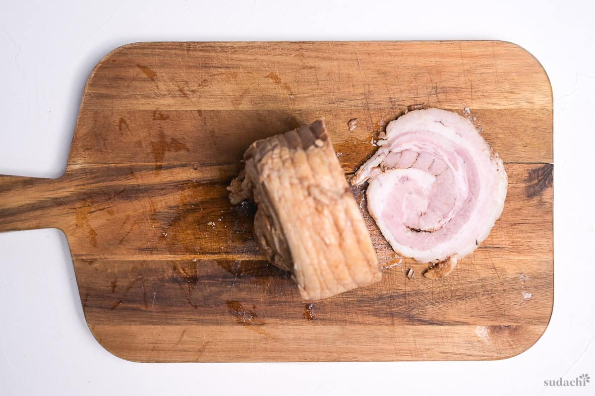 a piece of homemade chashu sliced on a wooden cutting board