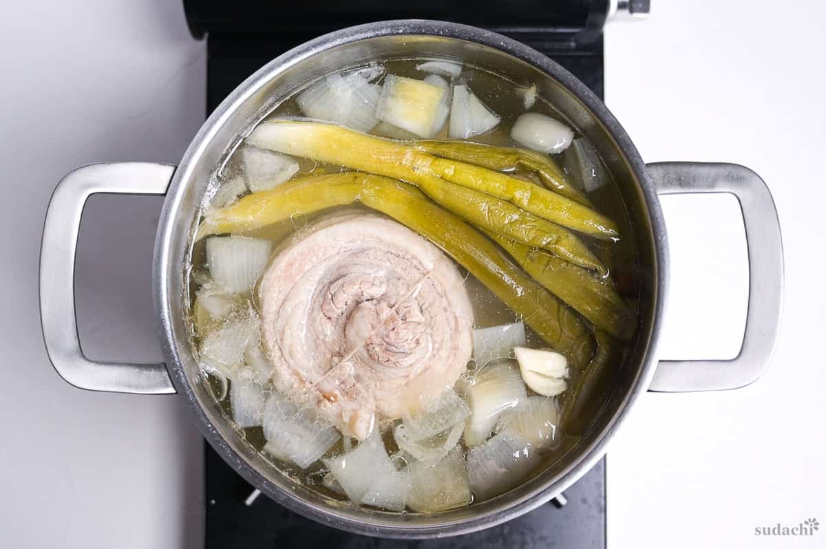 Simmering pork belly in stock to make chashu