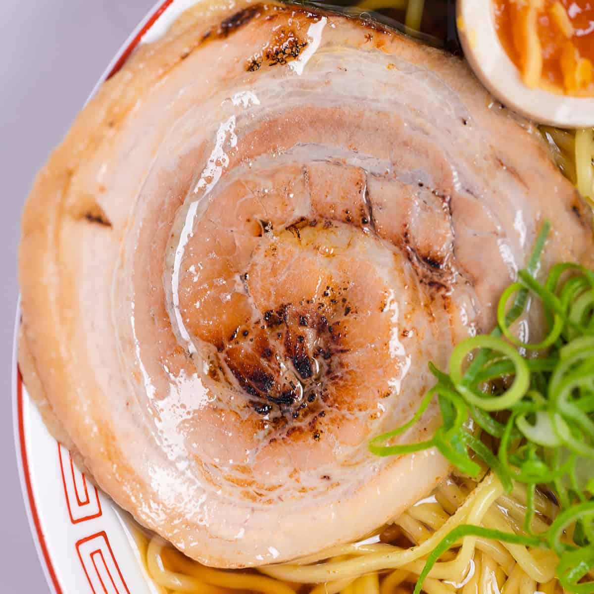close up of lightly charred pork chashu in a bowl of ramen