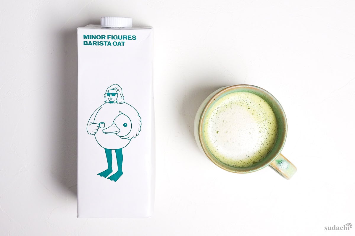 oat milk matcha latte next to a carton of minor figures barista oat milk