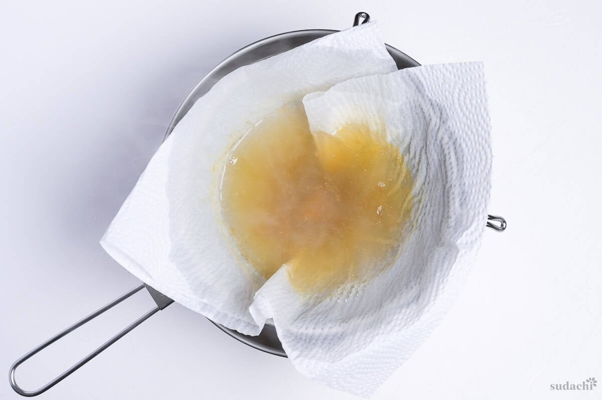 strained ramen broth in a sieve lined with kitchen paper to catch small flakes of bonito