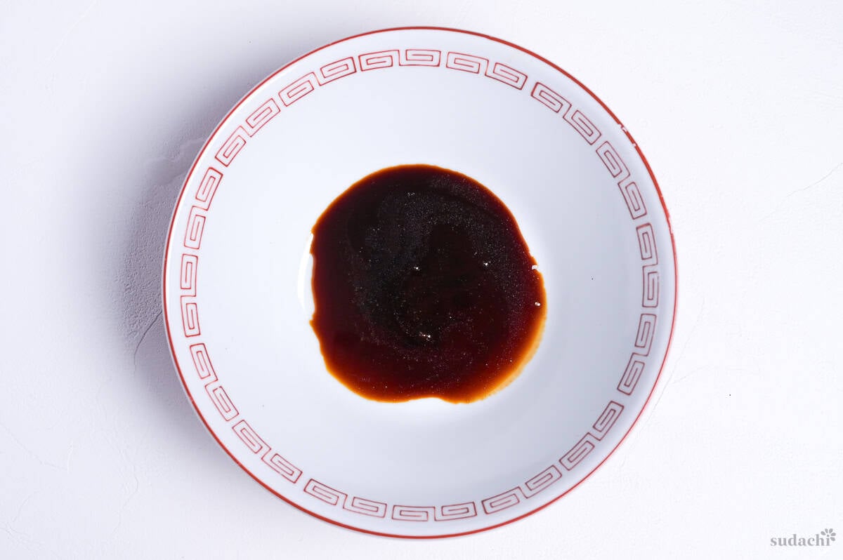 shoyu ramen tare in a white ramen bowl with red design on rin