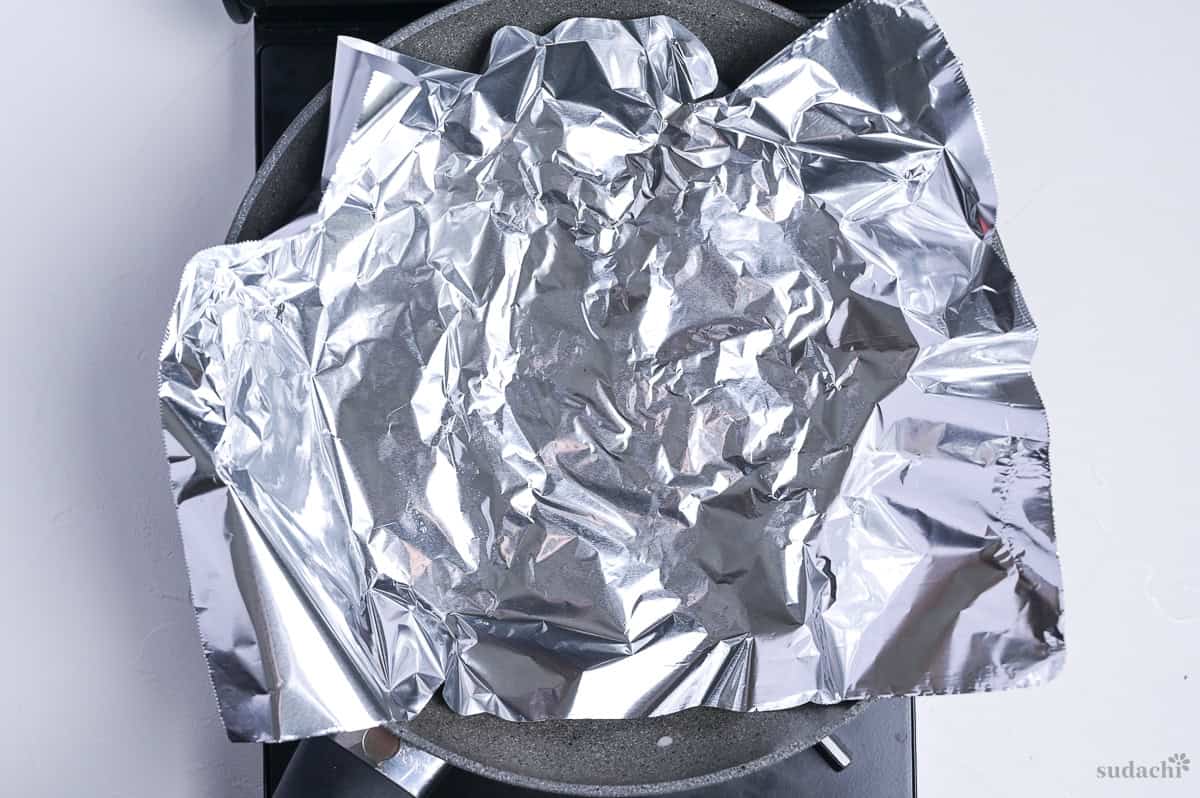 chicken skin in a frying pan topped with foil