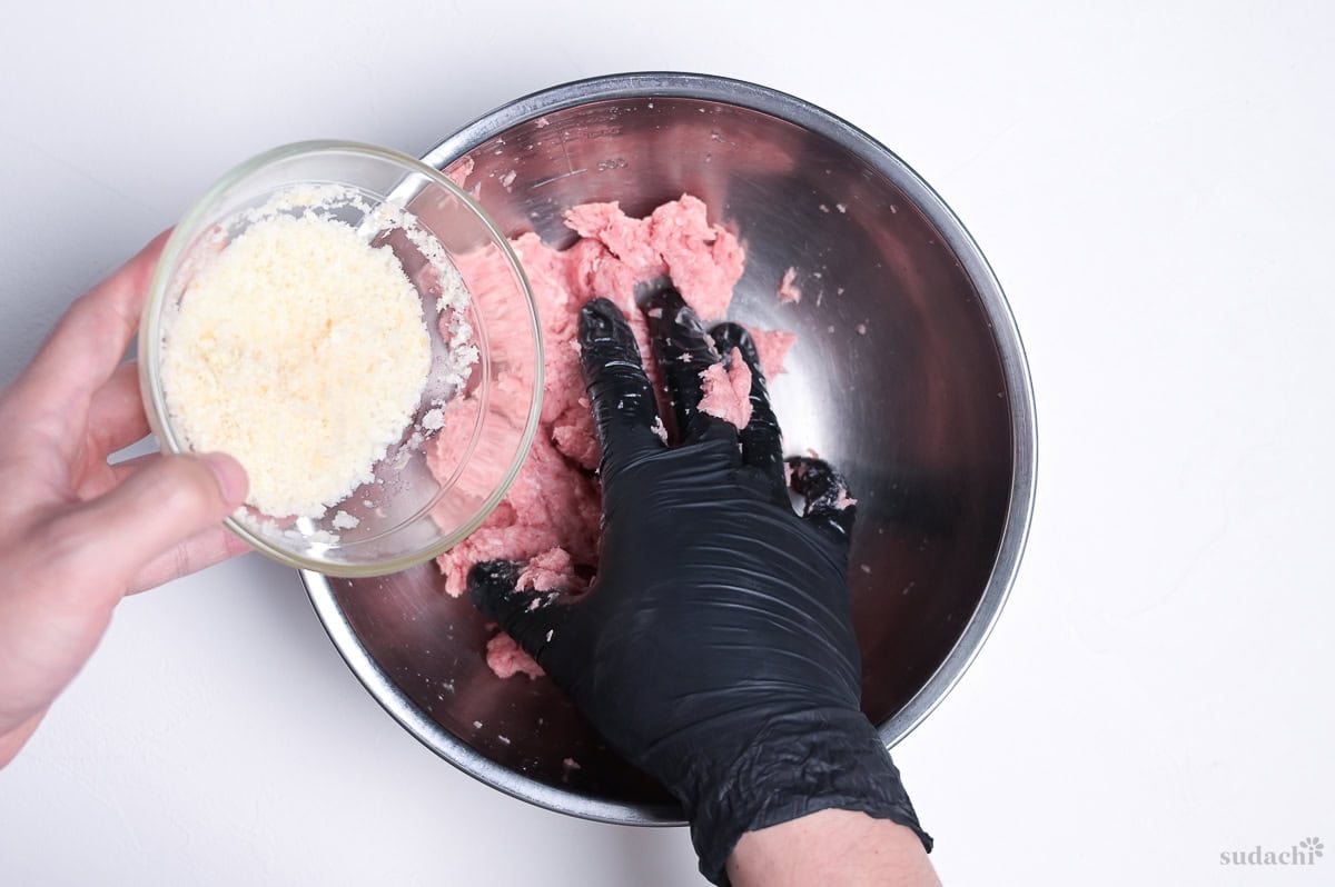 Adding soaked panko panade to ground pork in a steel mixing bowl