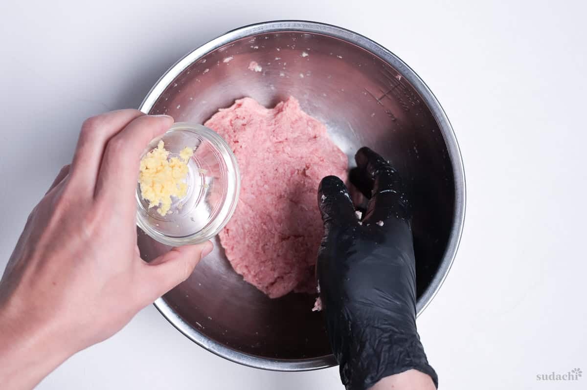 adding grated ginger to kneaded ground pork to make teriyaki burgers