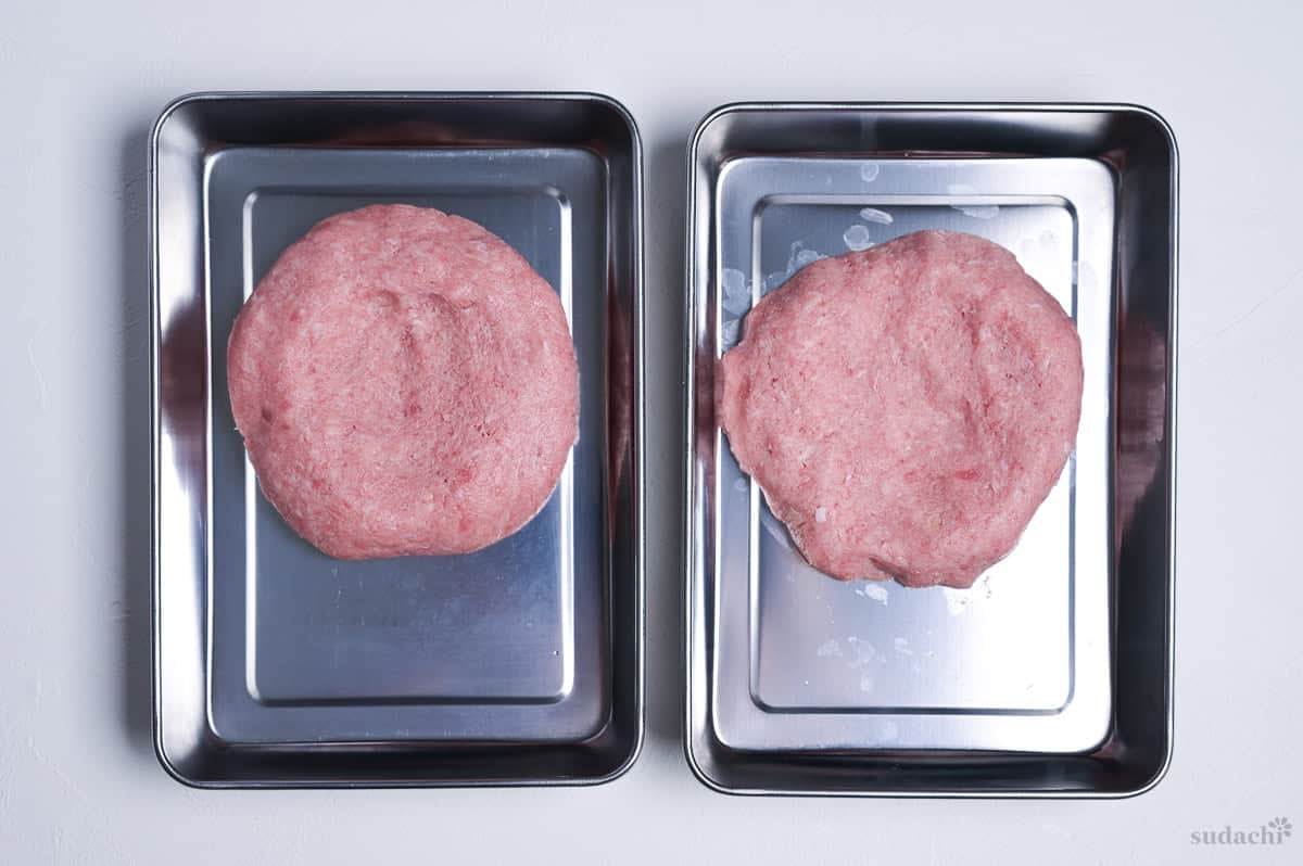 two ground pork patties shaped and placed in steel containers