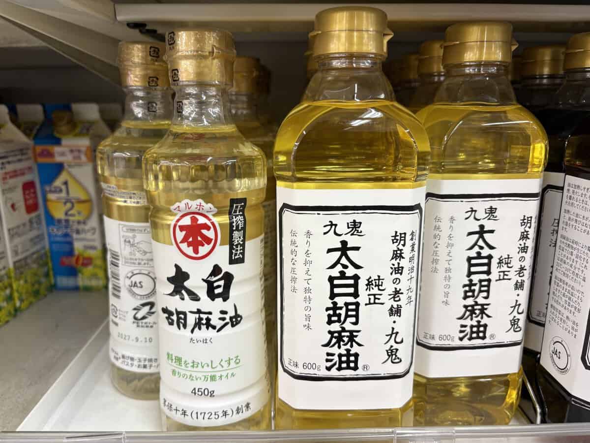 Japanese sesame oil bottles on a supermarket shelf, featuring Maruhon Taihaku pure sesame oil