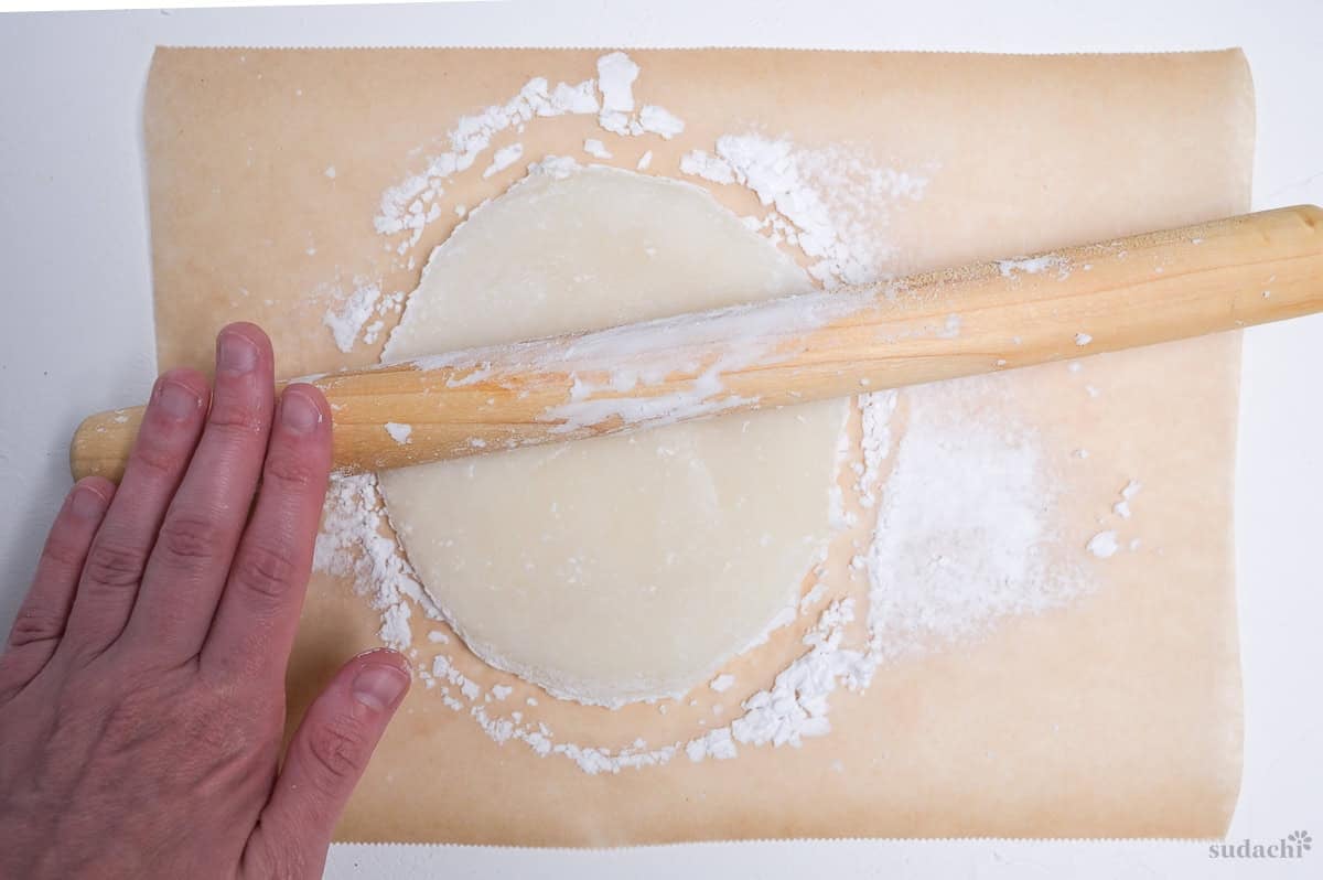 Rolling out daifuku rice flour dough (gyuhi) on parchment paper dusted with corn starch