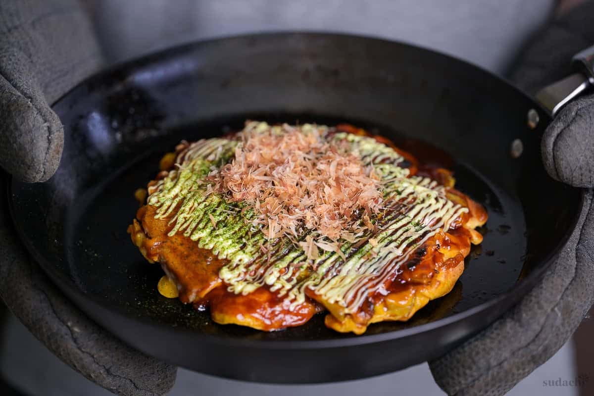Yuto Omura holding up homemade okonomiyaki in a cast iron pan