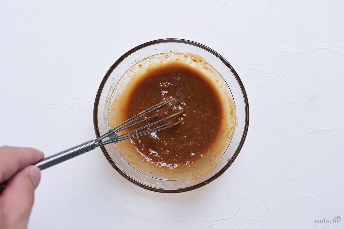 Miso whisked with broth in a small glass bowl.