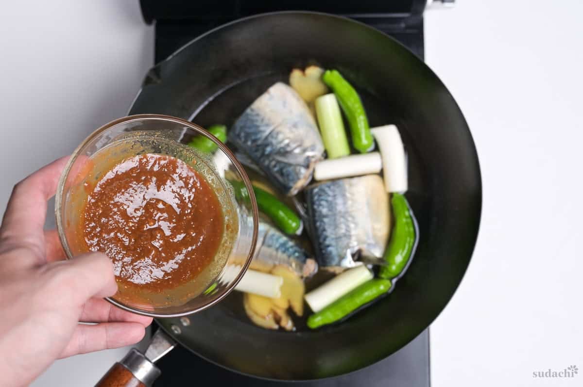 Pouring miso mixture into pan with mackerel fillets.