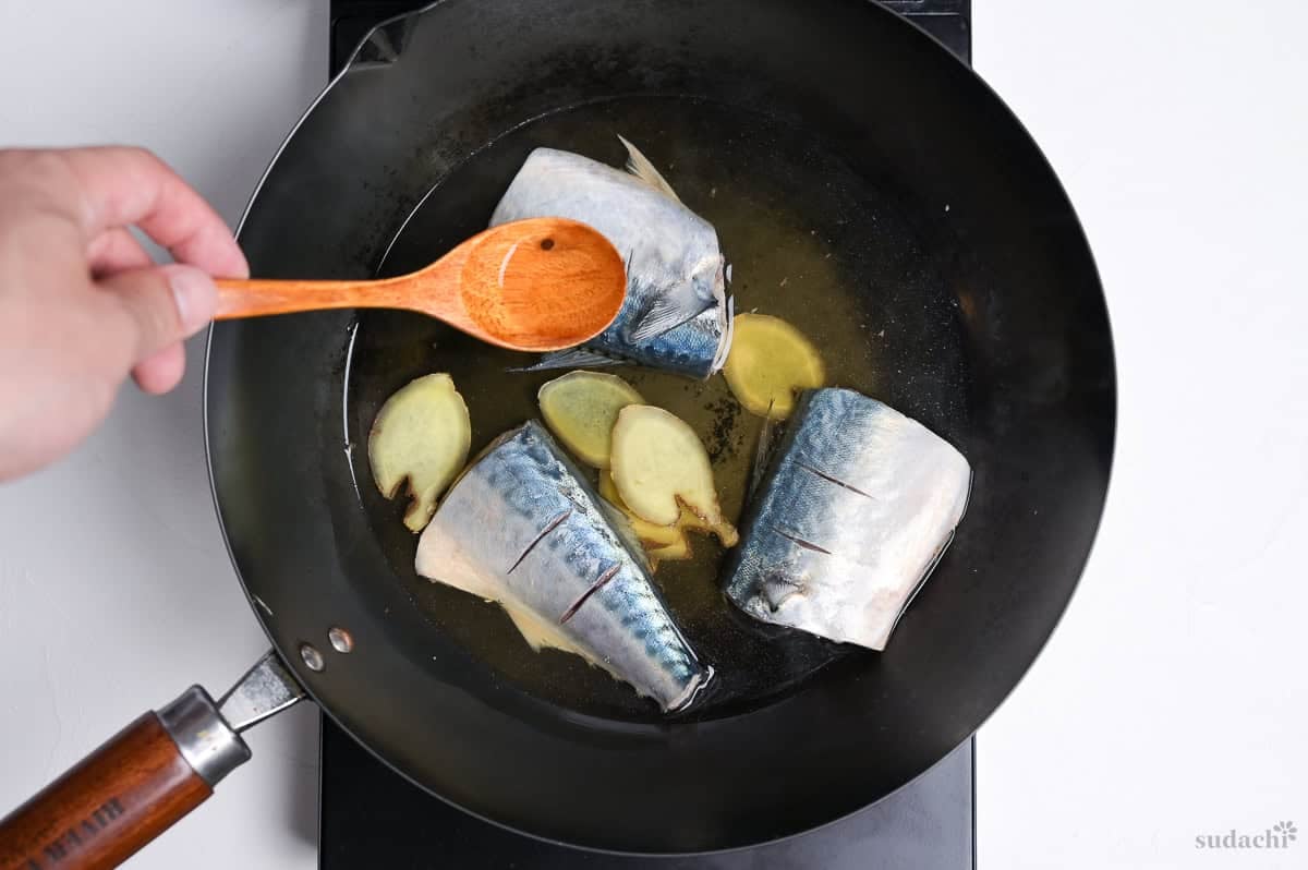 Basting the top of mackerel fillets with cooking liquid from the pan.