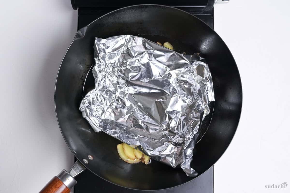 Simmering mackerel fillets in a pan covered with foil.