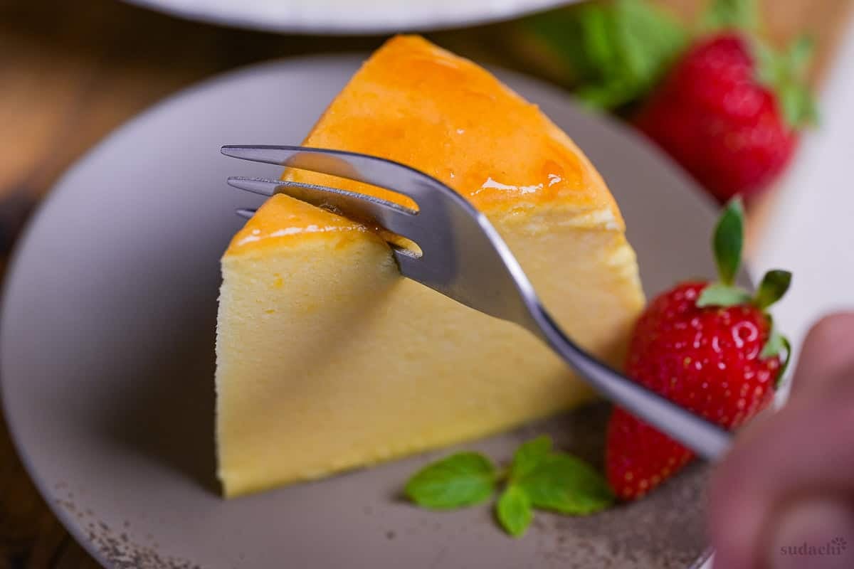 A dessert fork cutting through Japanese soufflé cheesecake