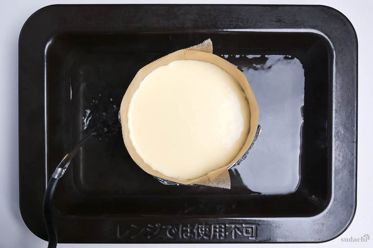 pouring hot water into roasting pan to make Japanese soufflé cheesecake