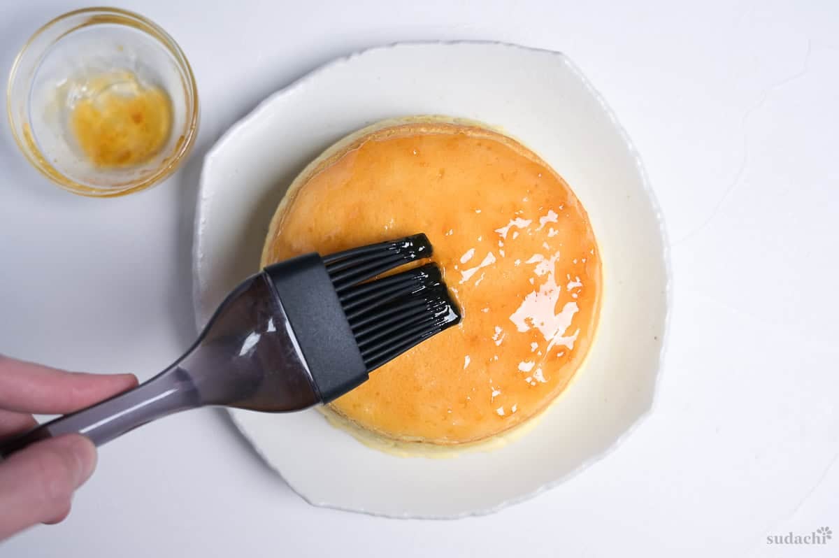 brushing the top of soufflé cheesecake with apricot jam