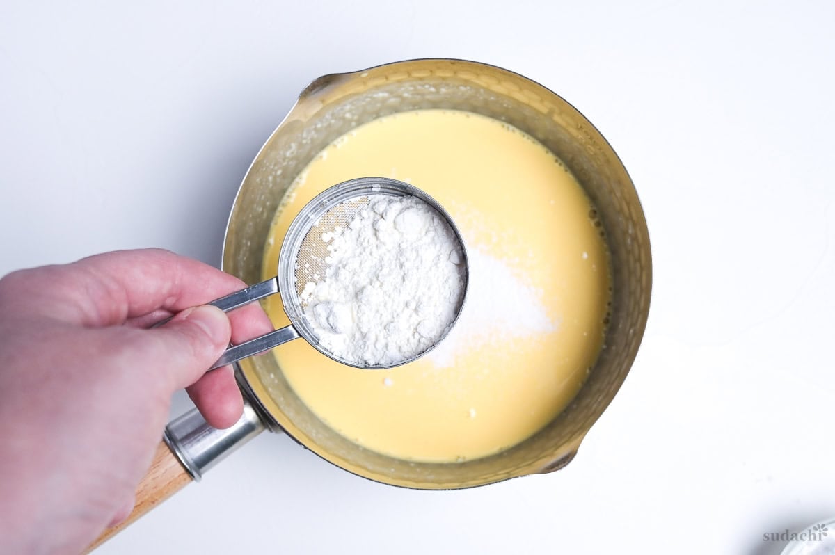 sifting flour and starch into soufflé cheesecake base
