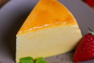 Japanese souffle cheesecake on a gray mottled plate with a mint leaf and a strawberry