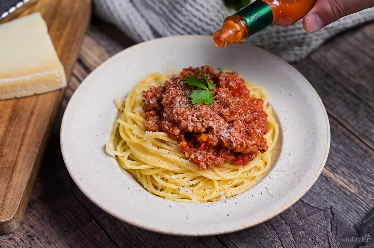 Sprinkling Tabasco chili sauce over Japanese spaghetti meat sauce