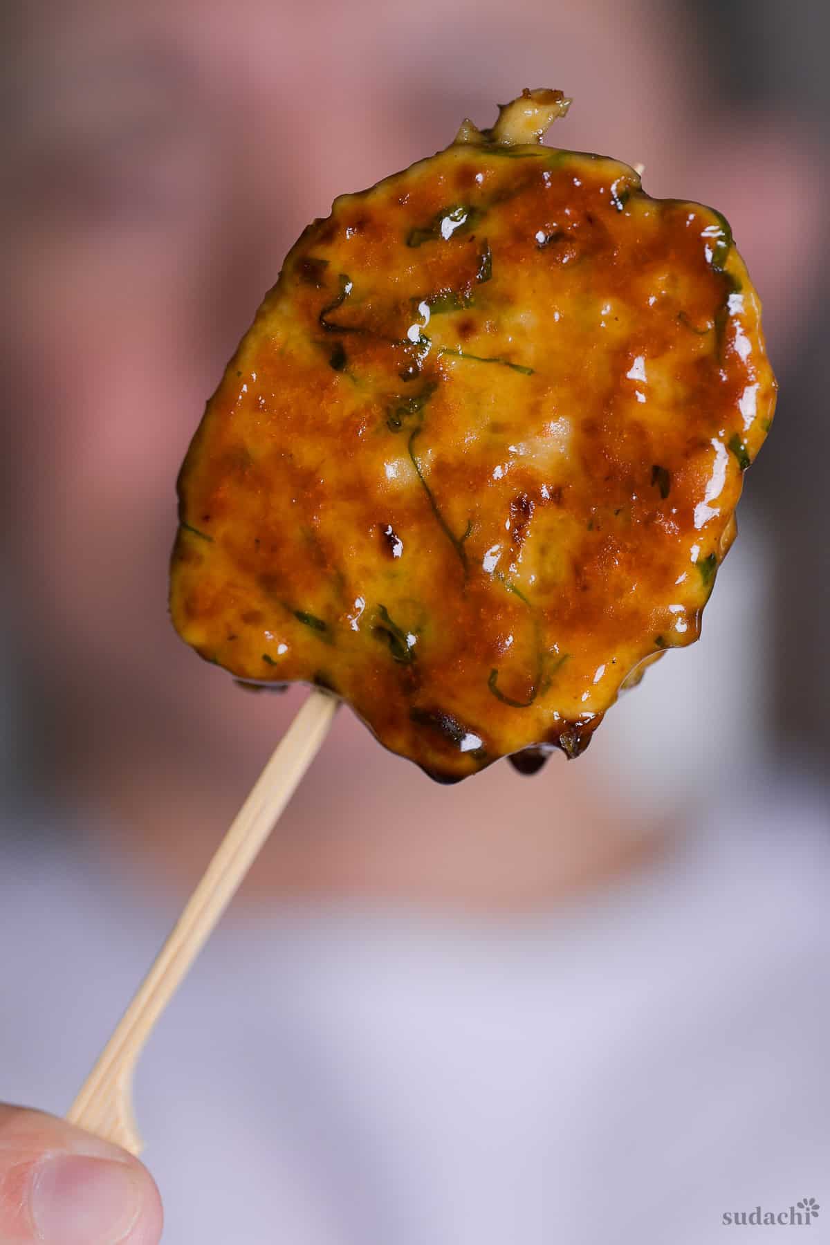 Yuto Omura holding up homemade tsukune (Japanese glazed chicken skewer)