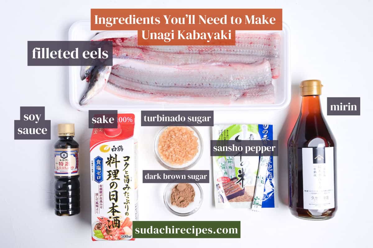 Ingredients needed to make unagi kabayaki on a white background with labels. From top to bottom, left to right: filleted eels, soy sauce, sake, turbinado sugar, sansho pepper, mirin, dark brown sugar.