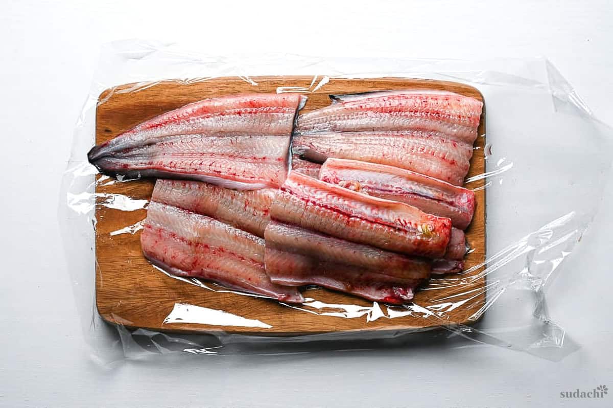 cut unagi on a wooden cutting board lined with plastic wrap