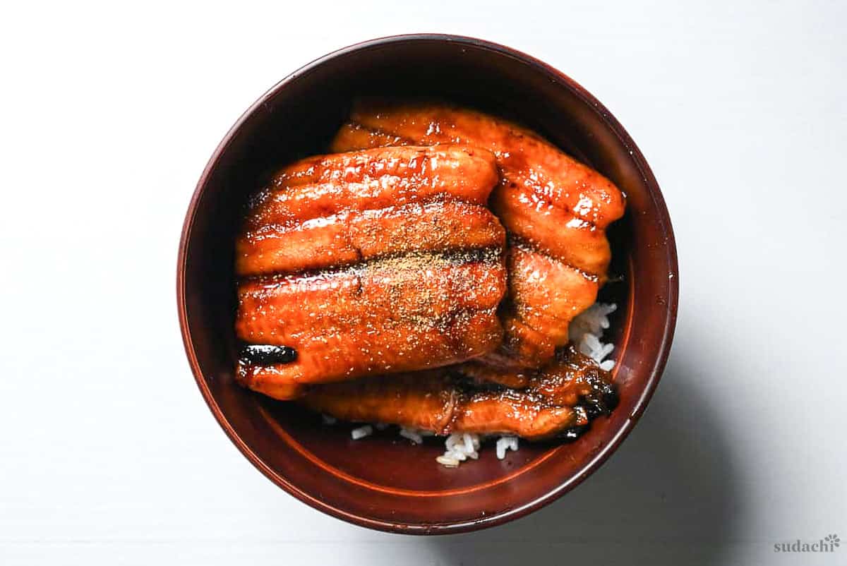 Unagi don sprinkled with sansho pepper, served in a red bowl