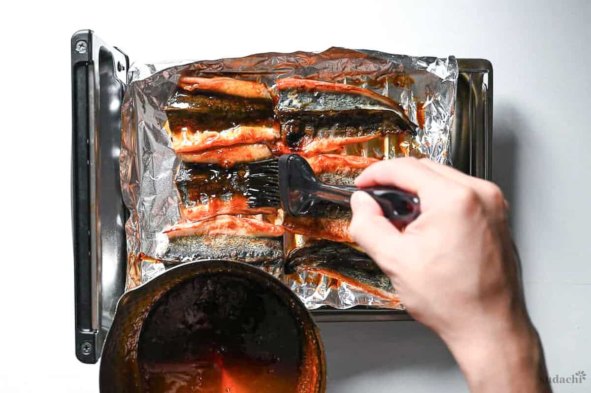 Yuto Omura brushing the skin side of grilled unagi with homemade kabayaki sauce