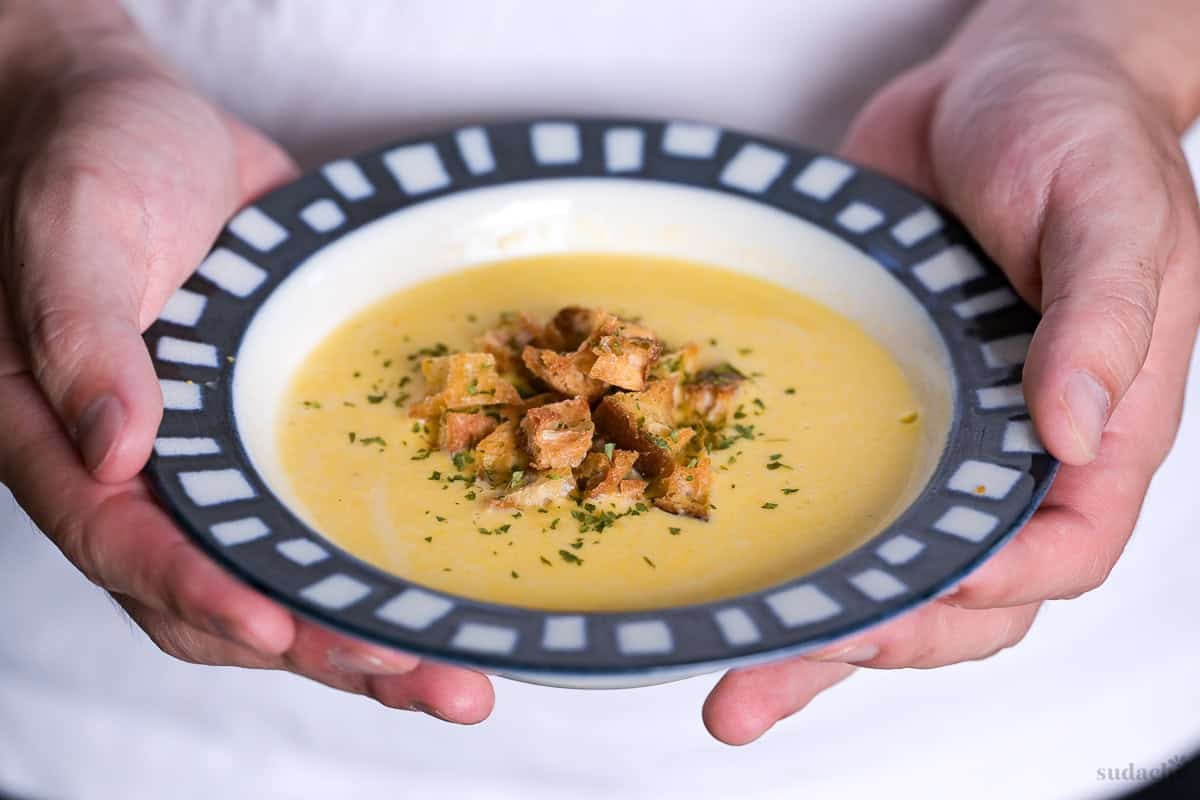 Yuto Omura holding up a bowl of Japanese corn potage topped with homemade croutons and dry parsley