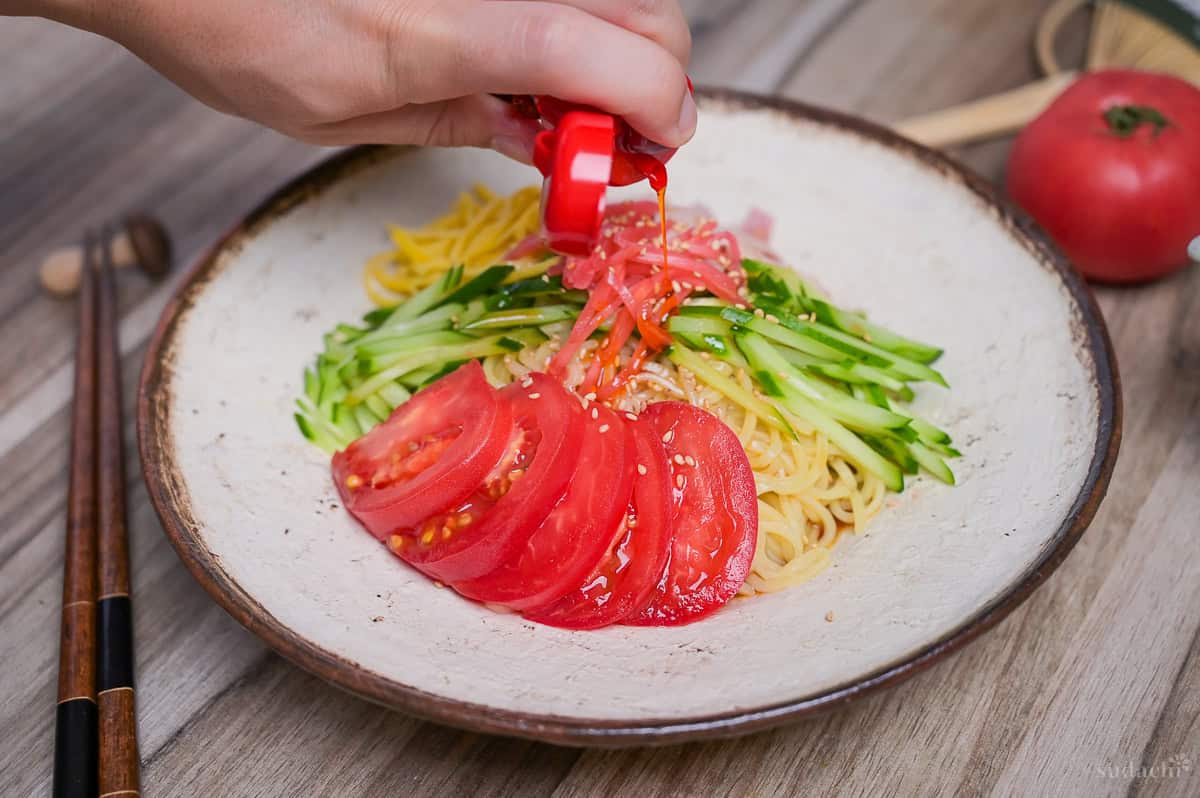 Pouring rayu (Japanese chili oil) over hiyashi chuka for a spicy kick.