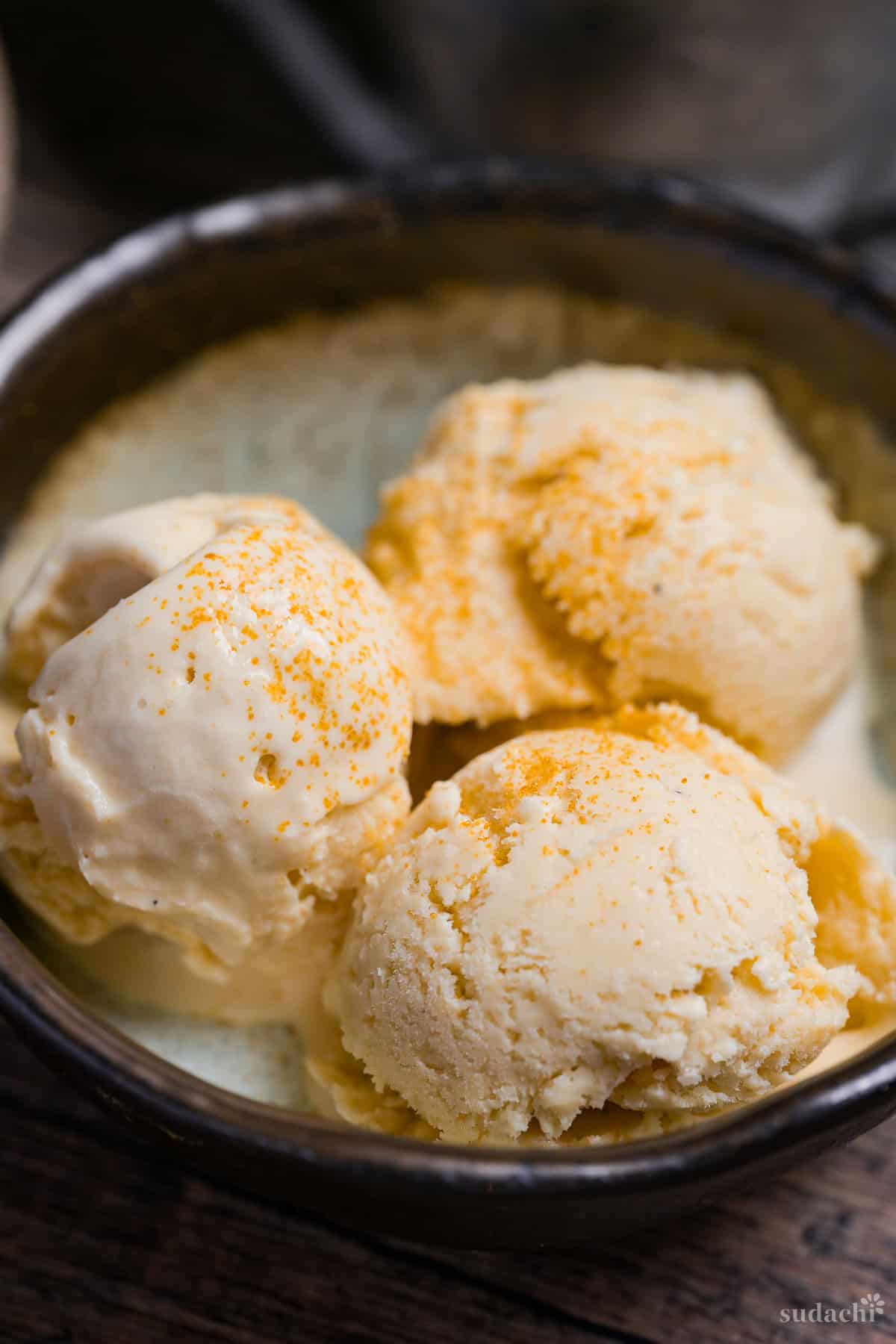 Close up of three scoops of homemade hojicha ice cream in a bowl with brown rim