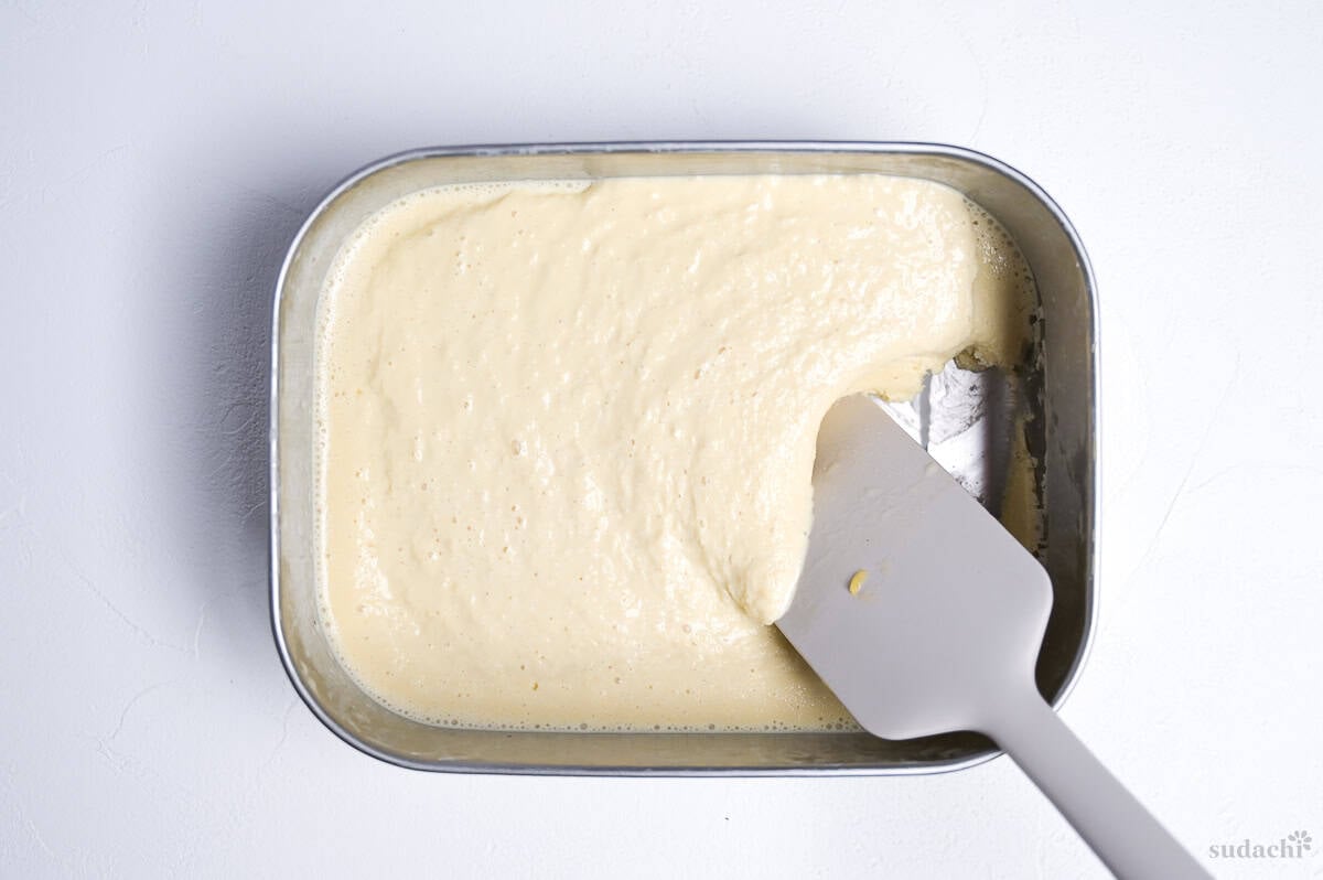 hand churning hojicha ice cream in a steel container