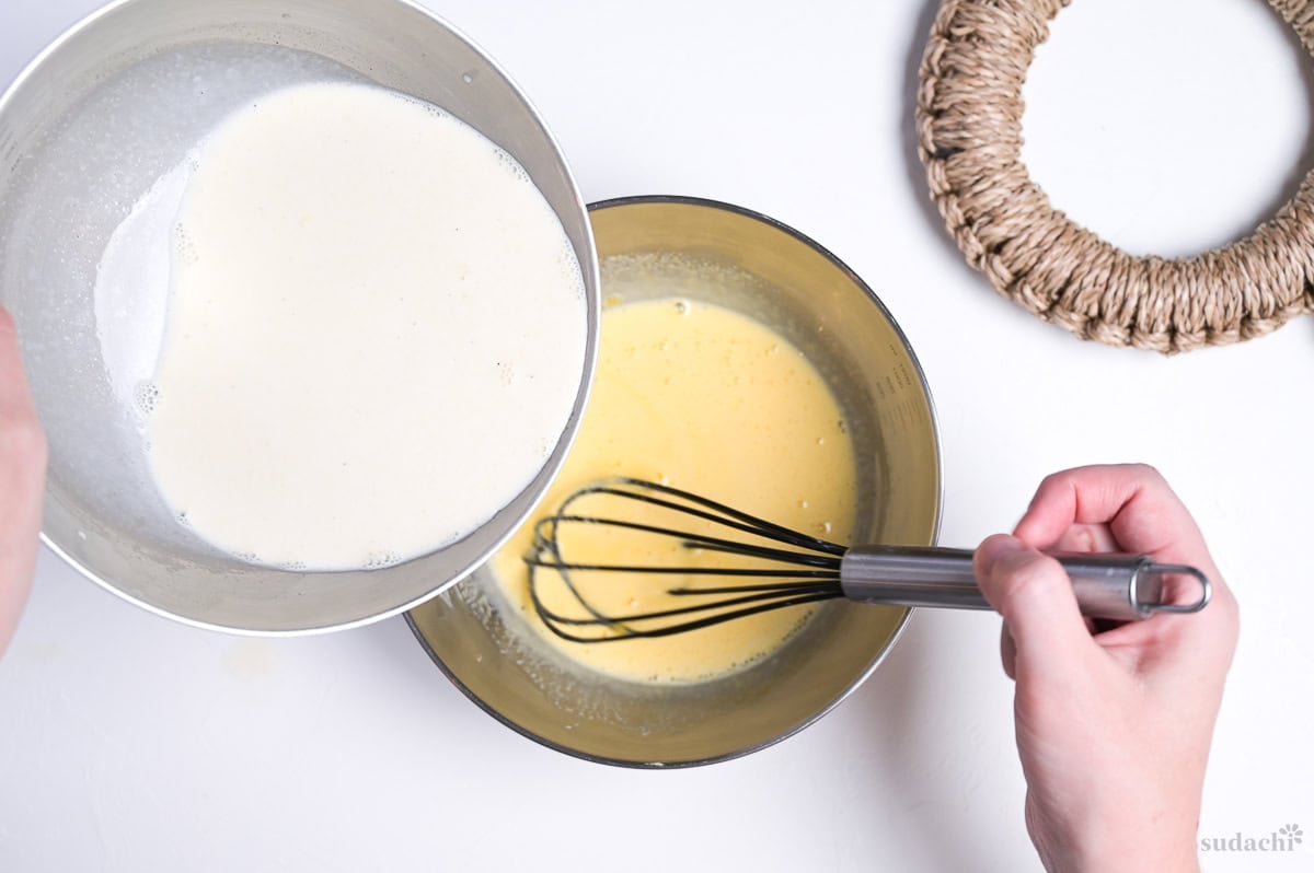 pouring hot hojicha milk and cream mixture into whisked egg yolks