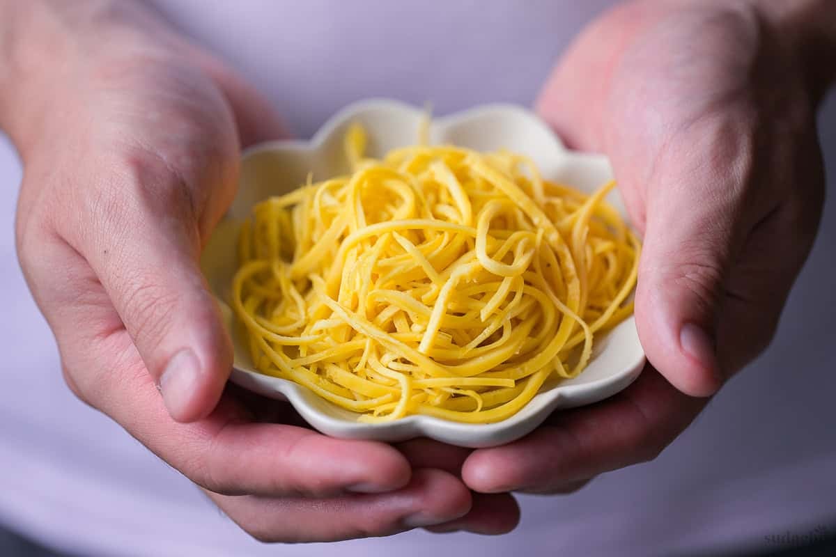 Yuto Omura holding homemade Kinshi Tamago (Japanese shredded egg crepe) in a white dish