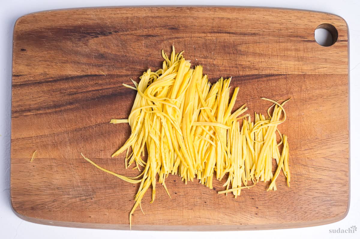 Japanese kinshi tamago (shredded egg crepe) cut on a wooden cutting board