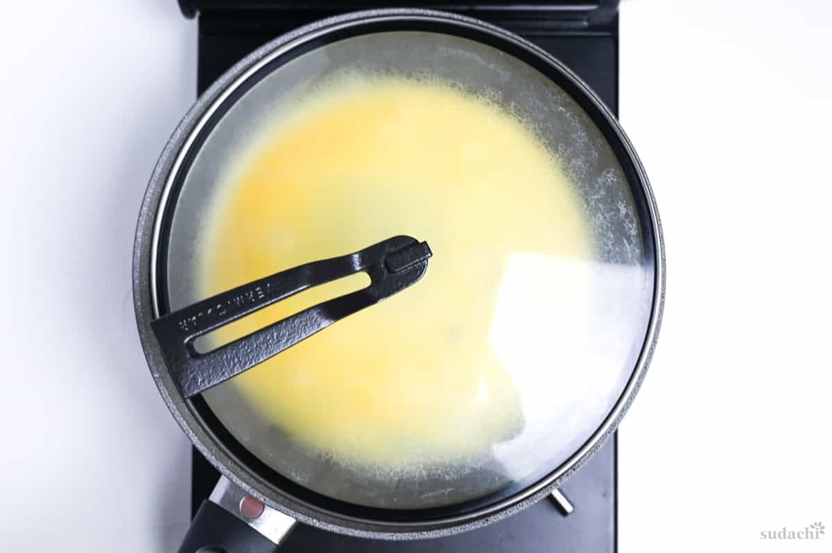 Kinshi tamago (Japanese shredded egg crepe) in a frying pan with a lid