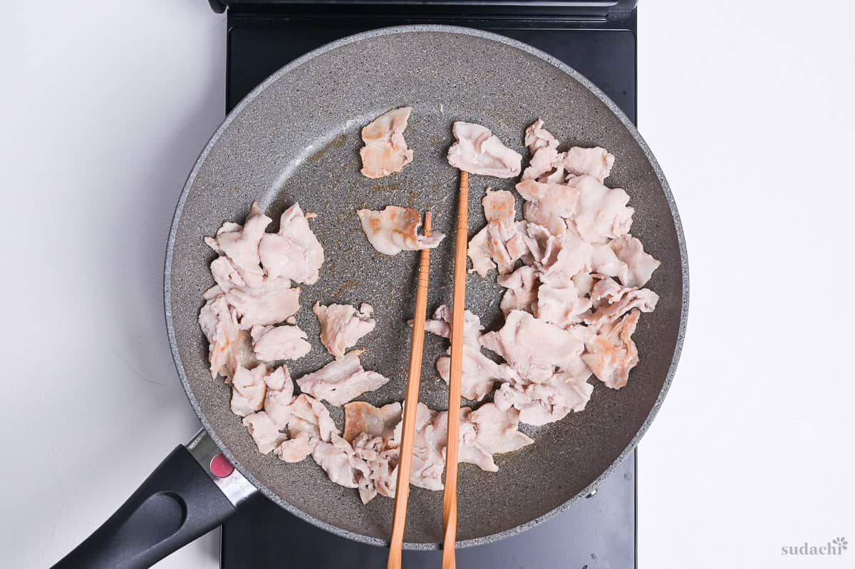thinly sliced pork seared in a frying pan on the stove top