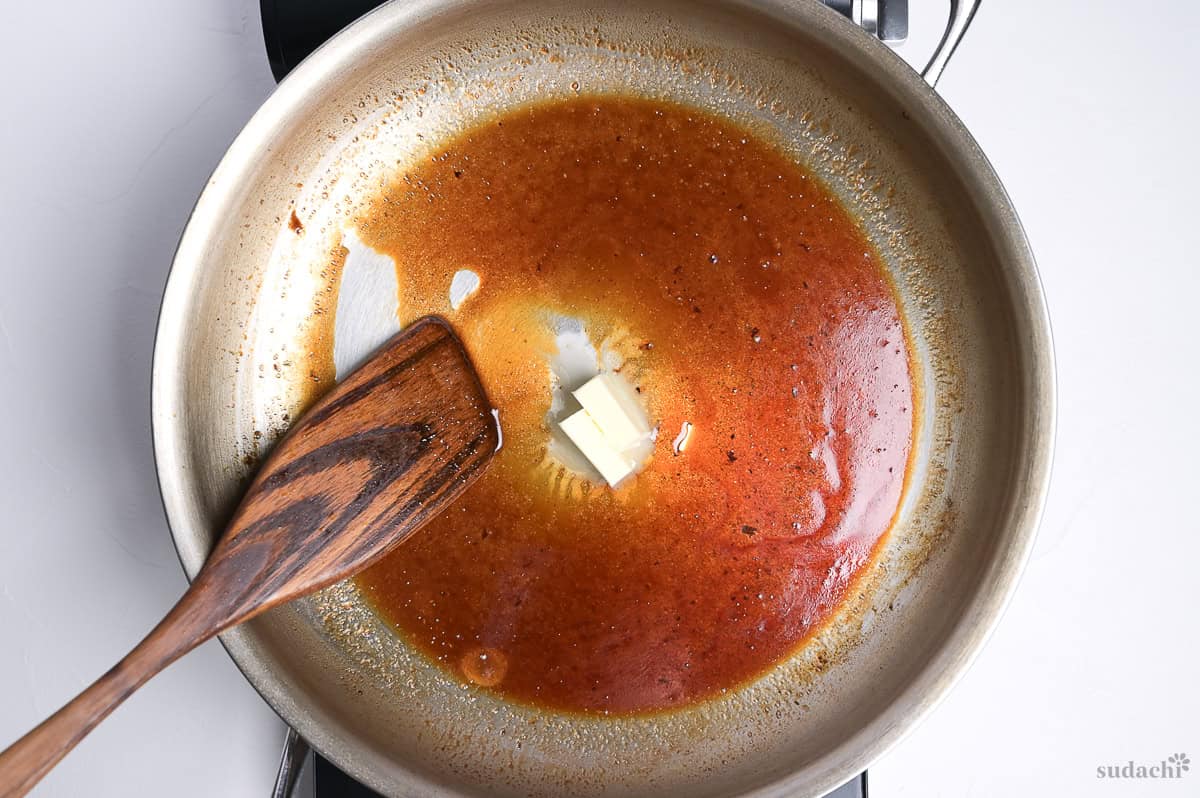 melting butter into steak sauce in a large pan on the stove top