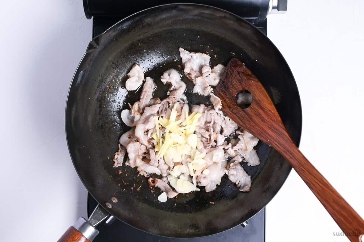 seared pork belly slices and aromatics stir fried in a wok