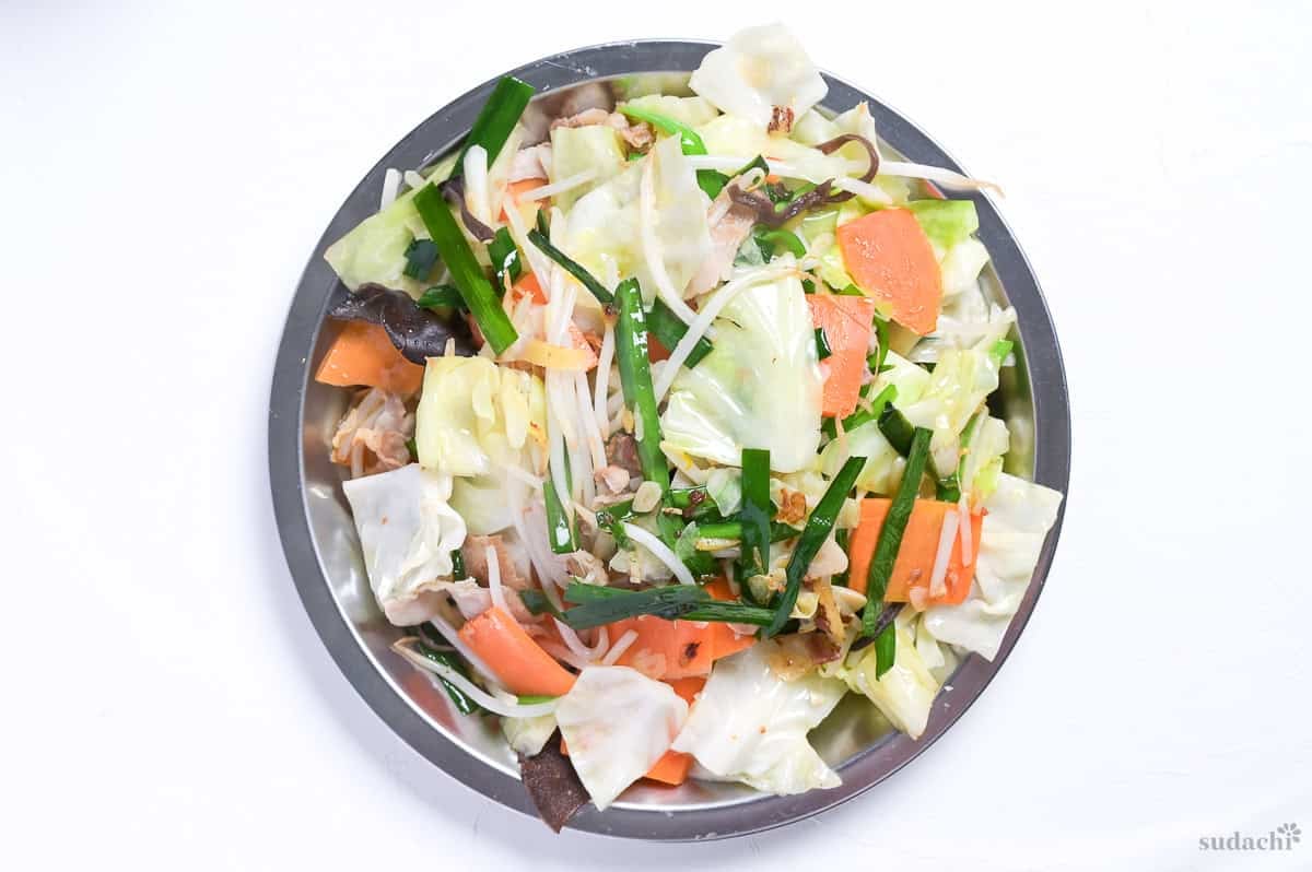 Stir fried vegetables and pork for tanmen on a steel prep plate.