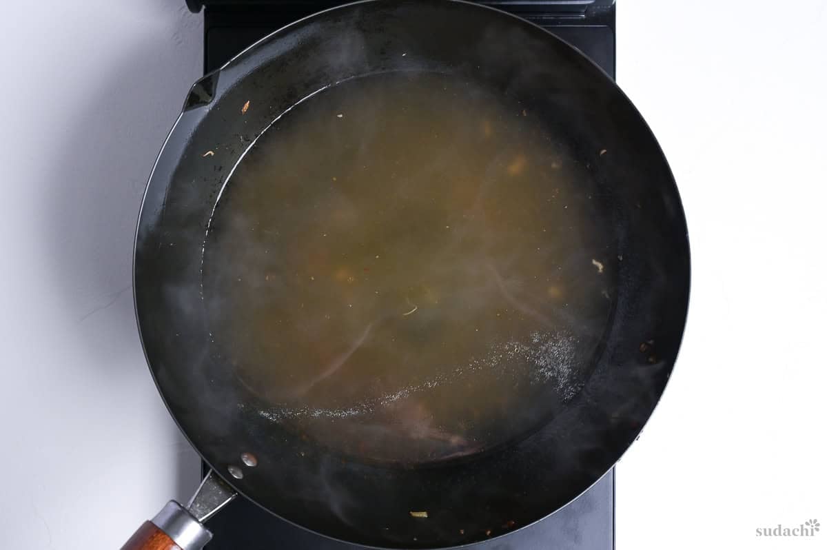 Heating broth for tanmen in a wok on the stove top.
