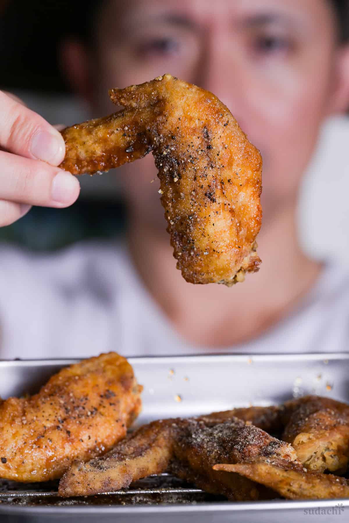 Yuto Omura holding up a Nagoya style deep fried chicken wing (Yamachan inspired tebasaki)
