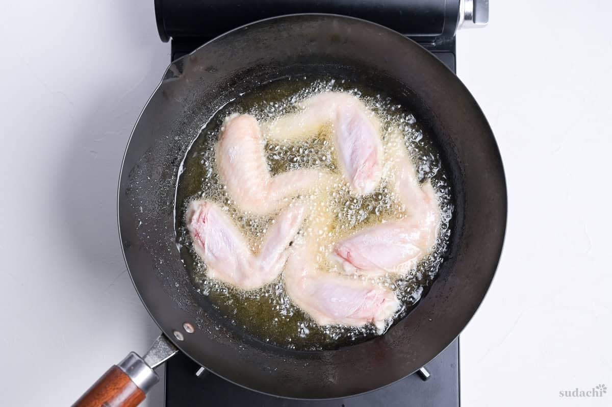 shallow frying flour-dusted whole chicken wings to make Japanese style tebasaki