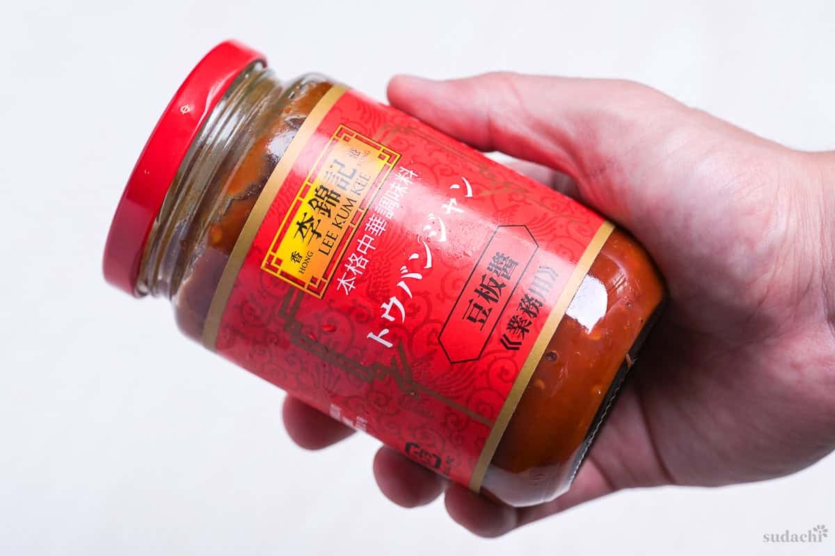 A hand holding lee kum kee tobanjan (label in Japanese)