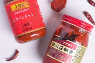 Two jars of tobanjan (doubanjiang, Chinese chili bean sauce) by Le Kum Kee and Youki surrounded by dried chilis